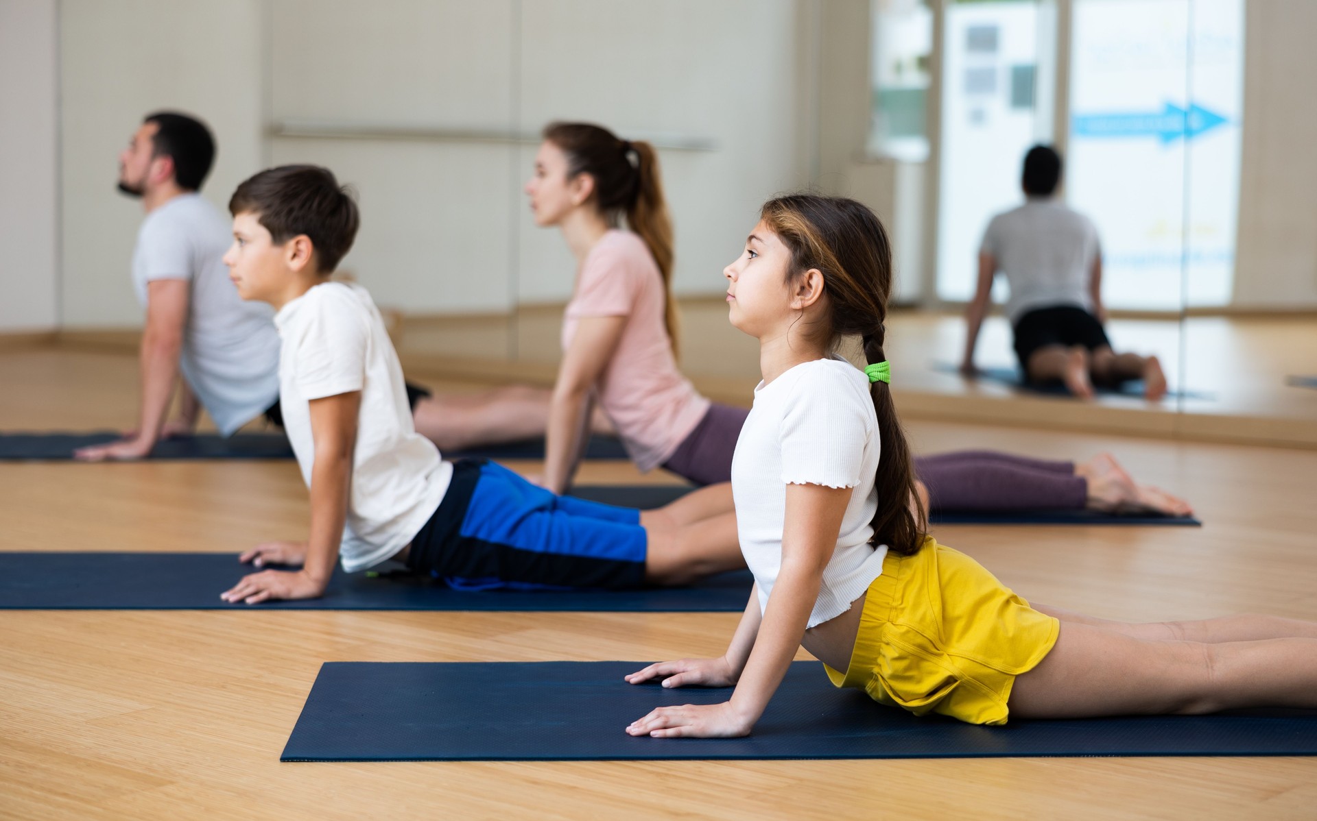 Girl doing stretching asana Upward Facing Dog during family yoga workout